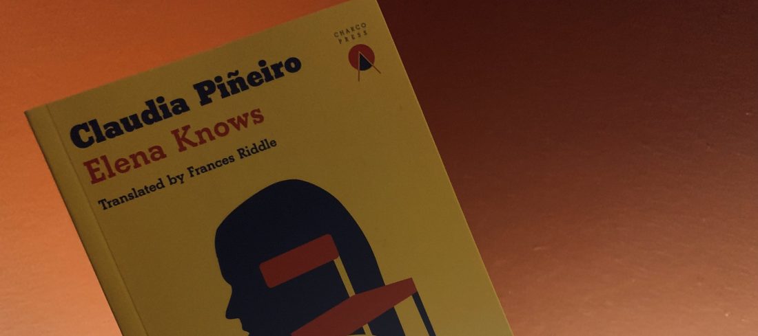 yellow book cover with woman's head on it, held against red background